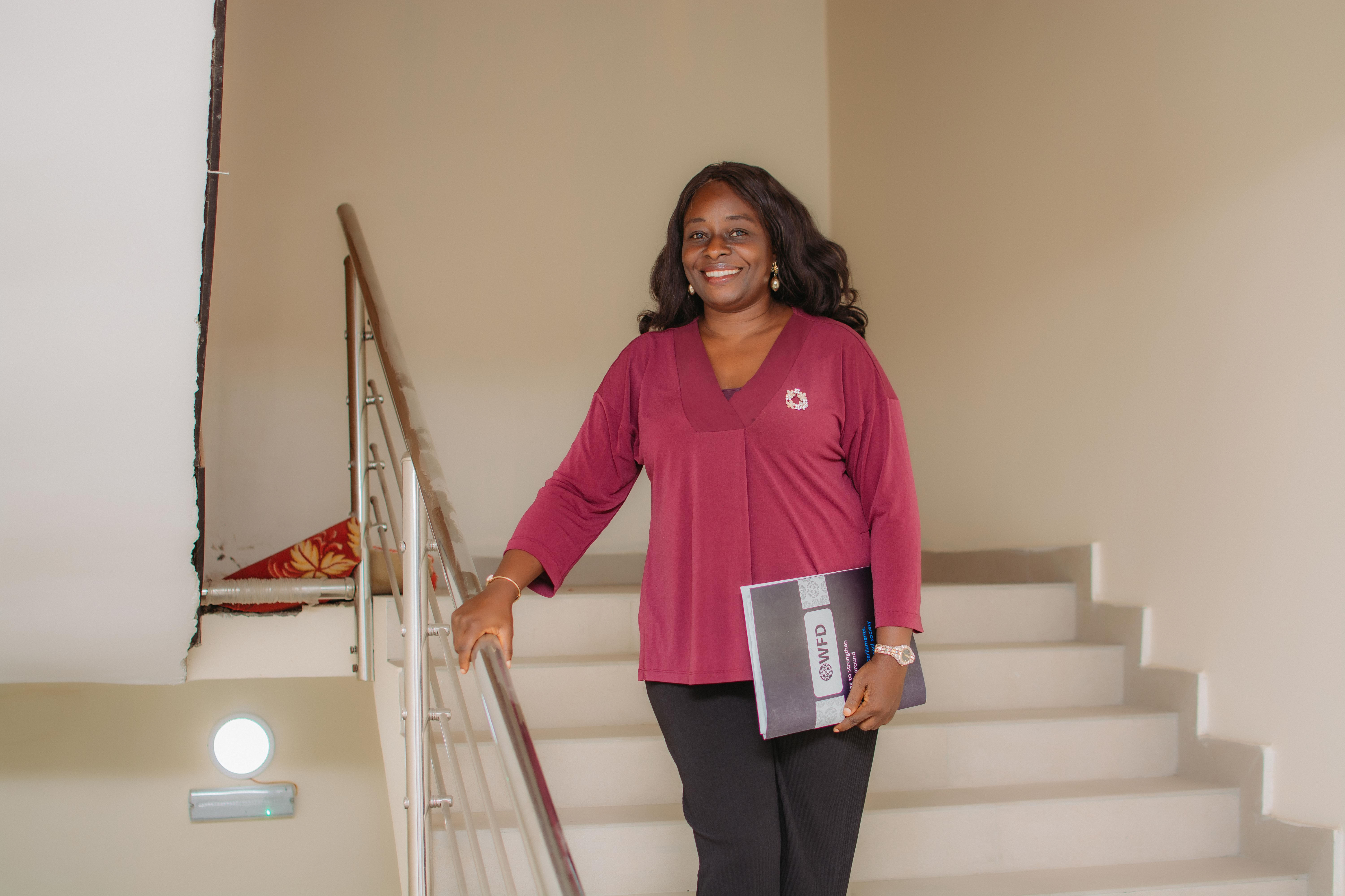 a woman stands on the stairs holding a document 