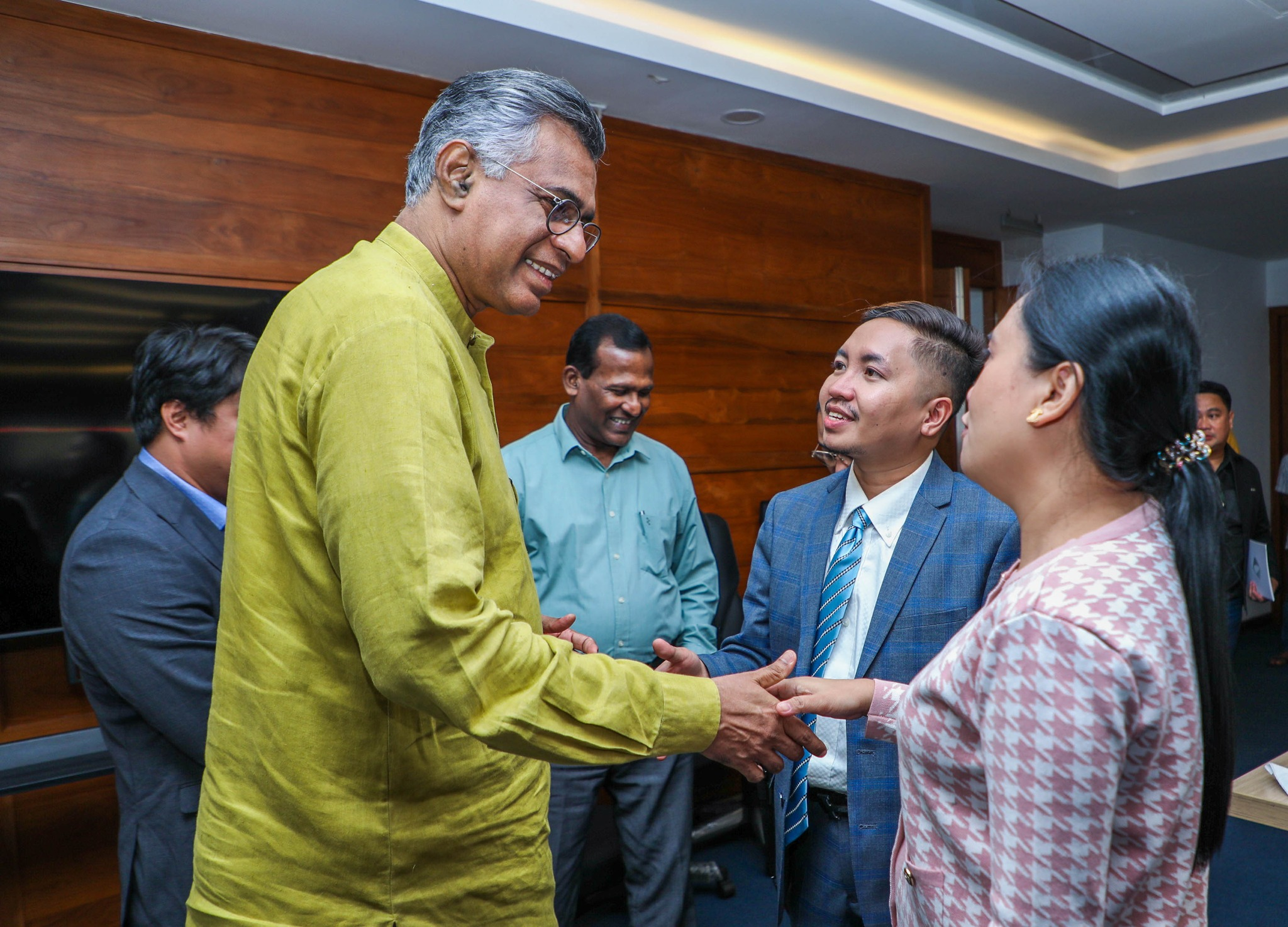 A group of people with two in the foreground shaking hands.