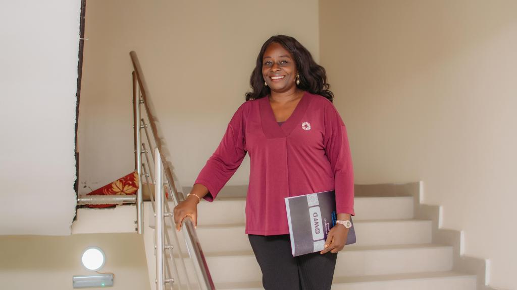 a woman stands on the stairs holding a document 