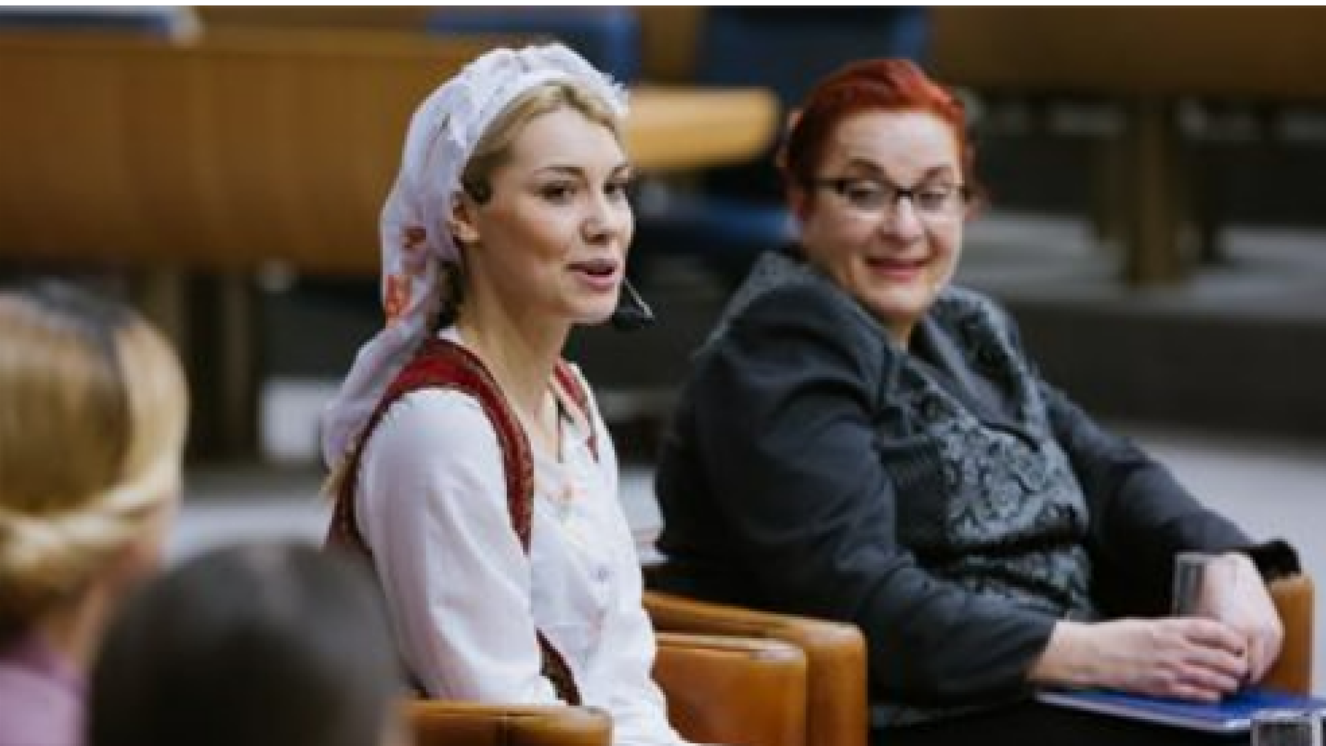 two women sitting next to each other, smiling and speaking1
